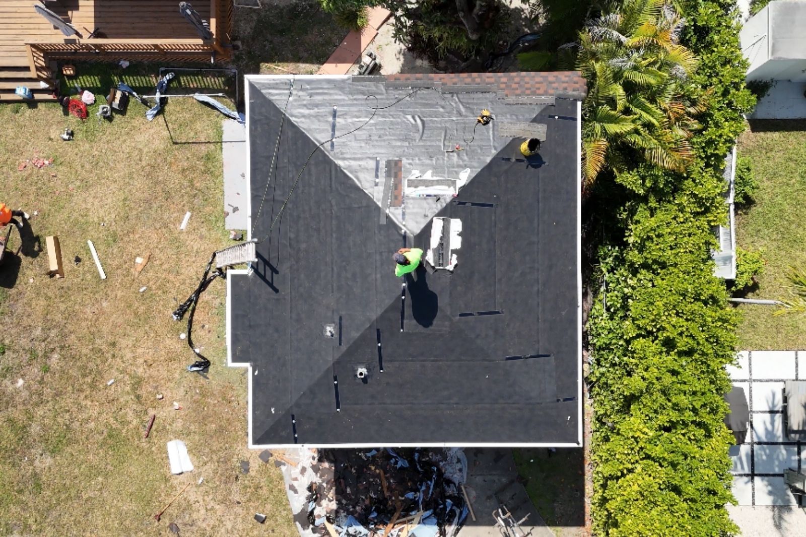 Aerial view of a shingle roof replacement in progress with underlayment installed before final shingles.