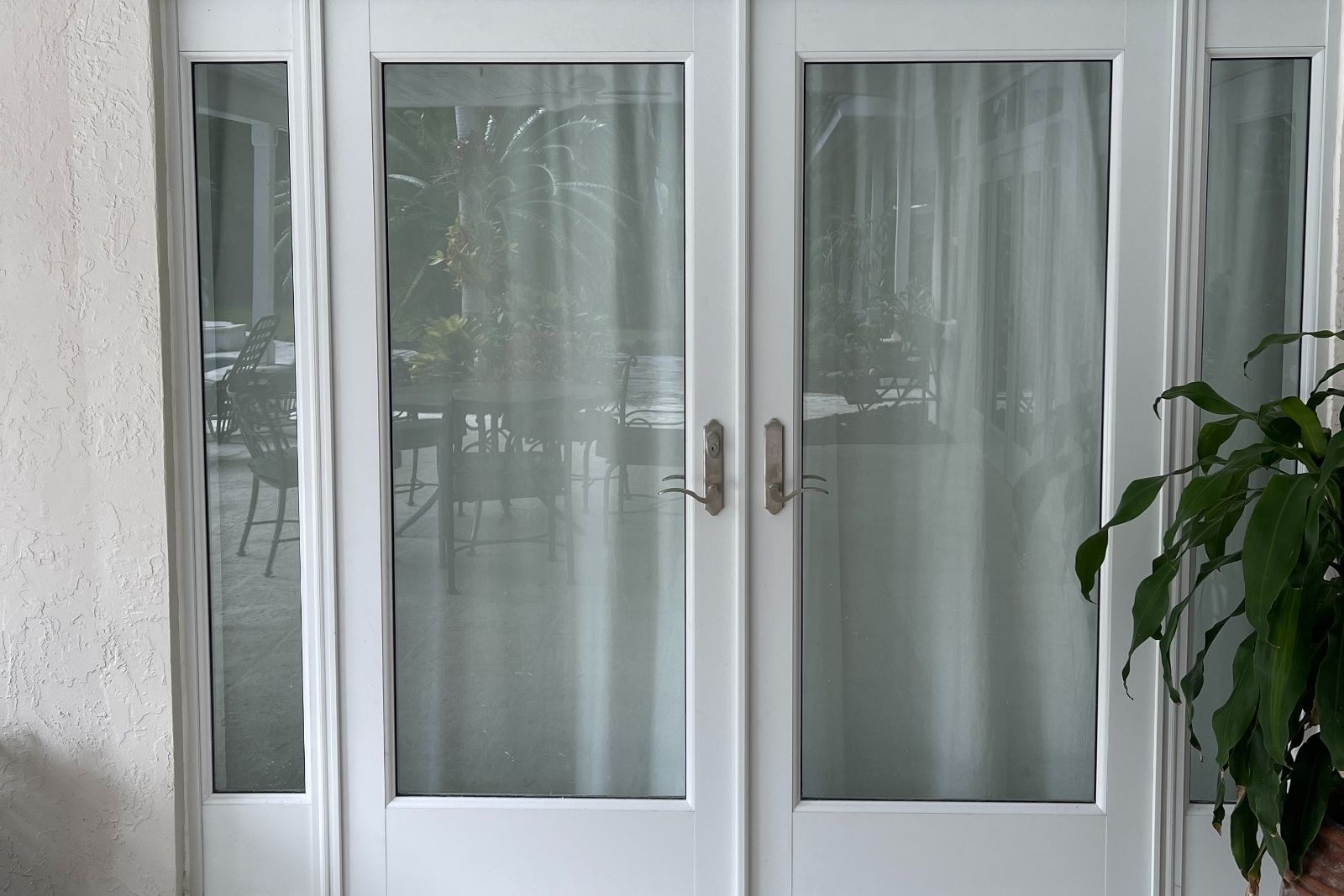 Close-up of white impact French doors with sidelites before replacement in Miami