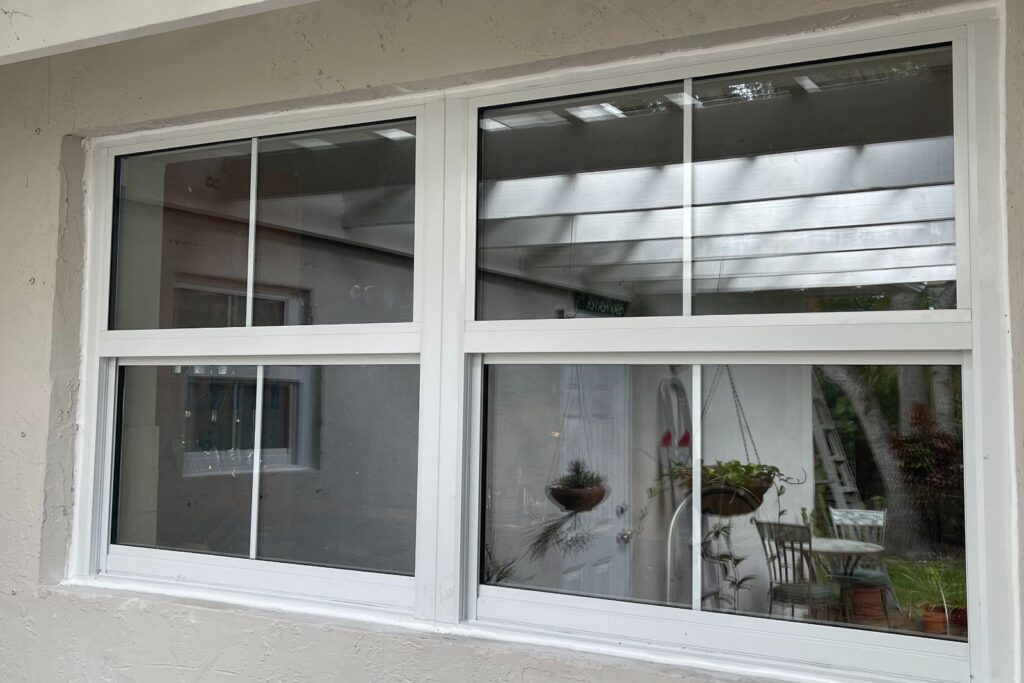 White impact windows installed in a wide opening with divided-lite look, clean trim and sealed edges