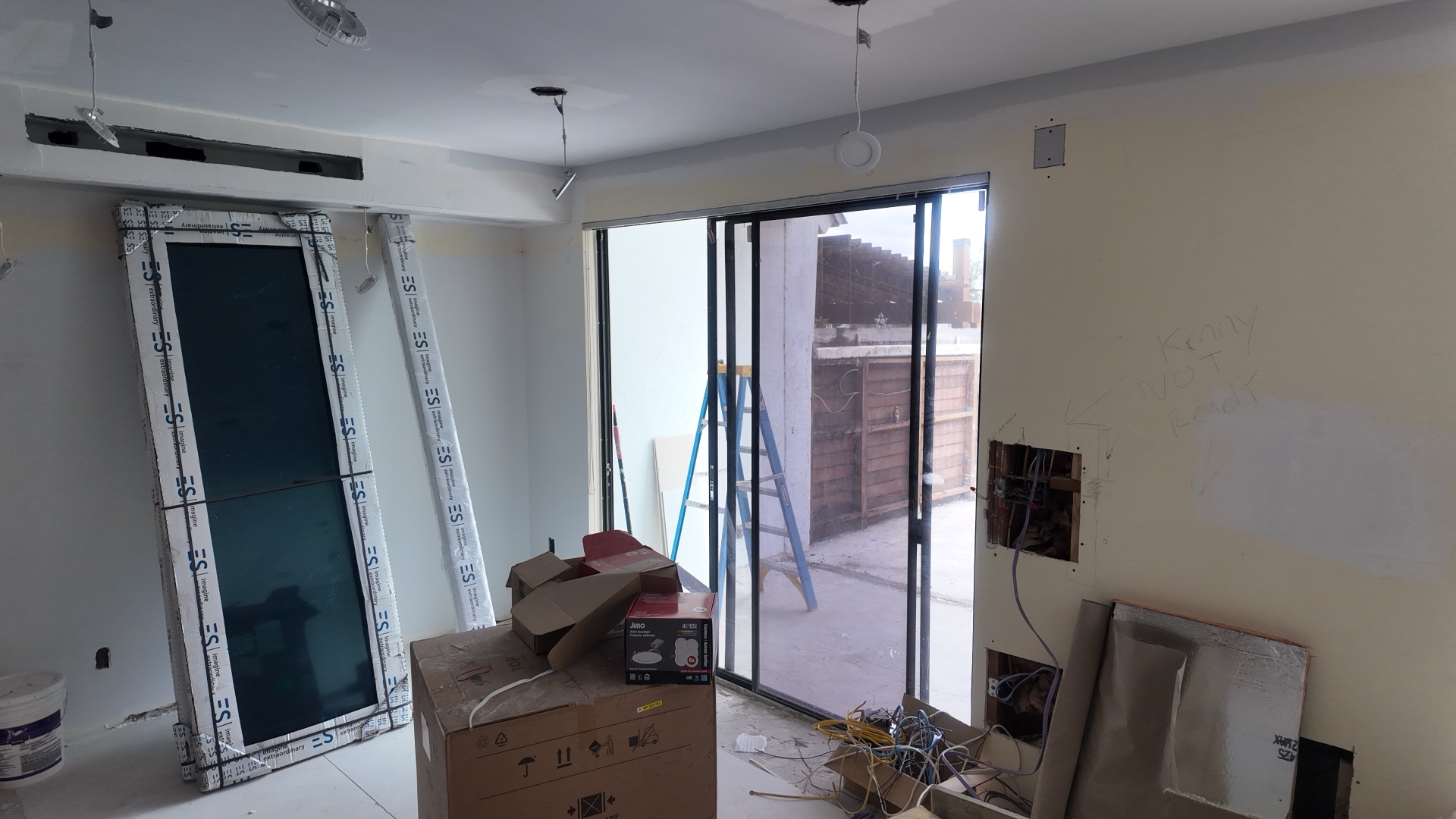 ES Windows impact glass panels staged inside a Miami-Dade home before installation, showing protective film and laminated units