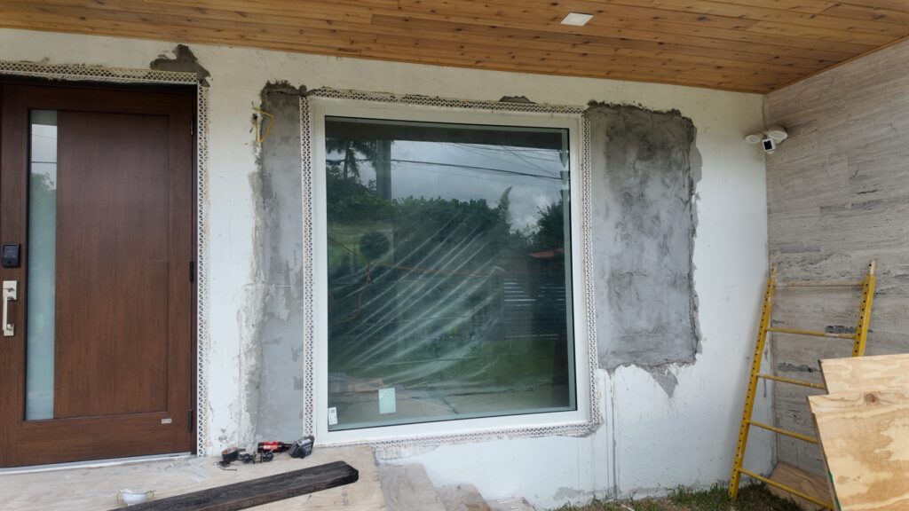 Impact window installation in progress on a Miami stucco home - Bigfoot Windows crew sets new aluminum frame impact picture window