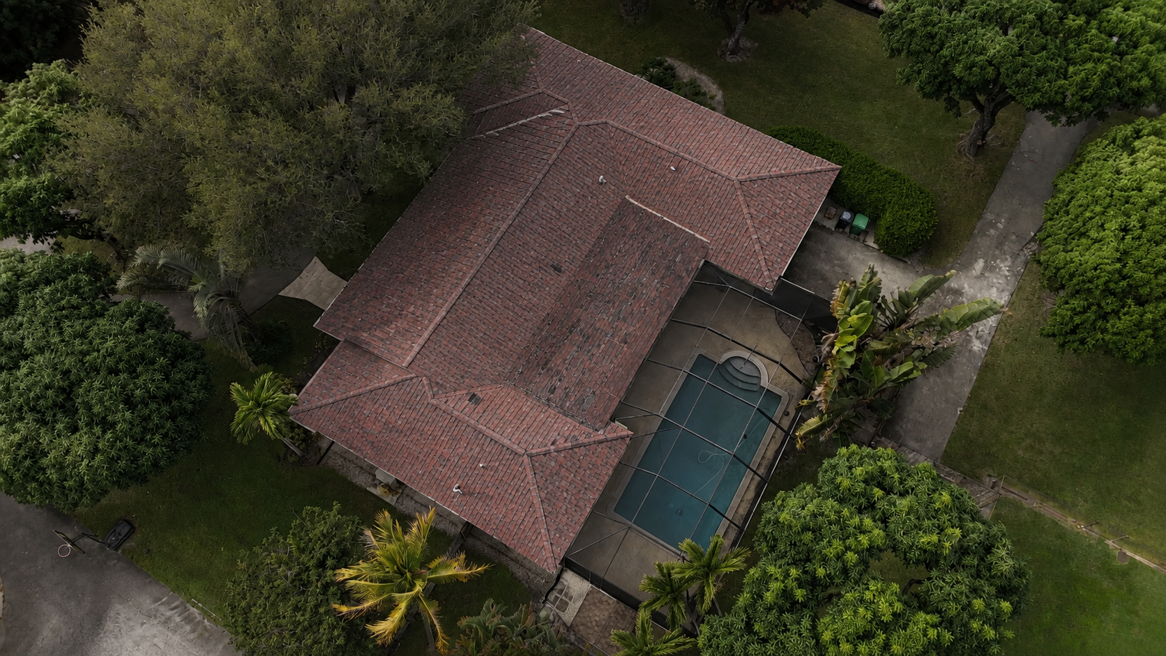 Before view of a house with a dark roof and screened pool