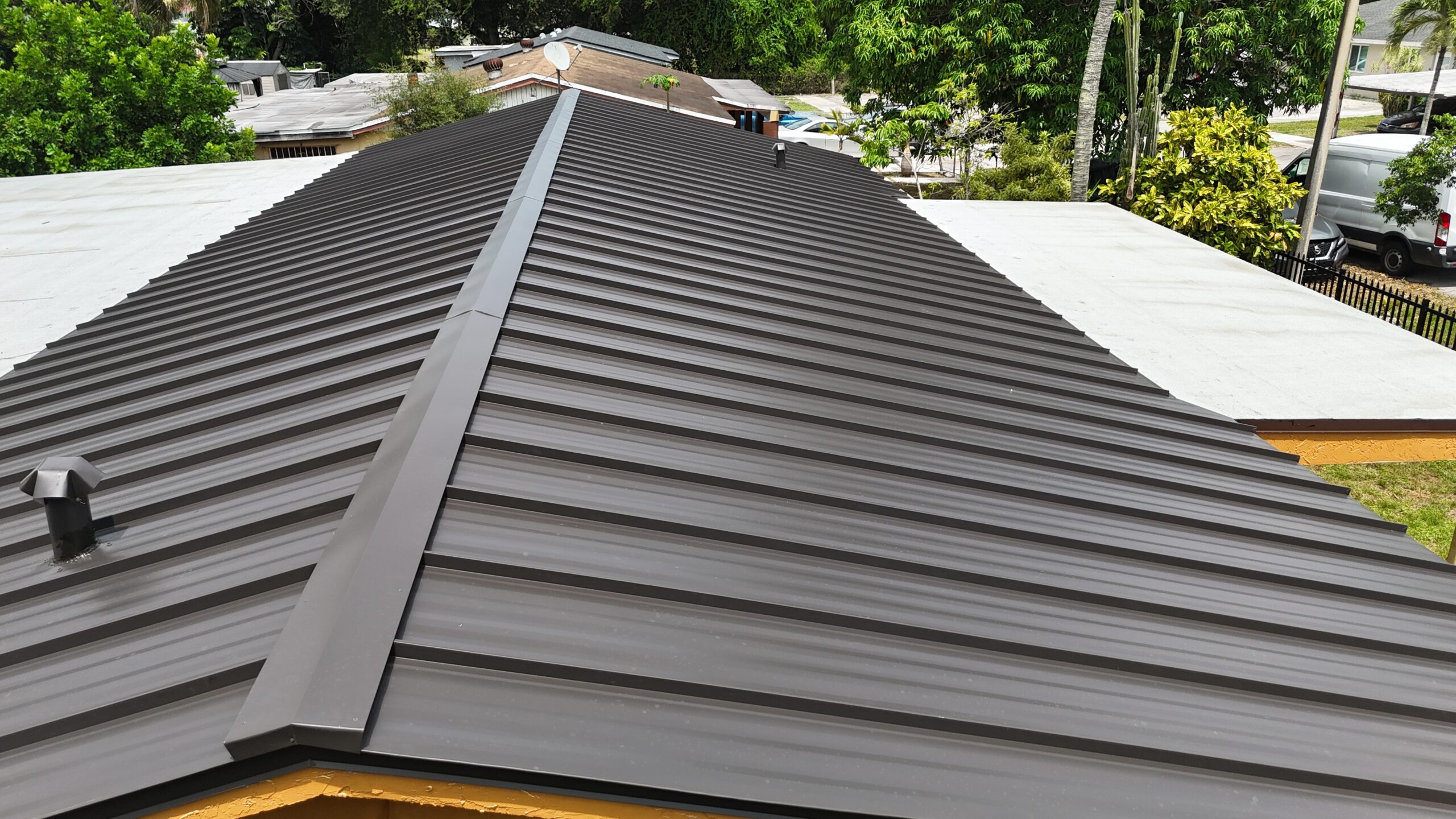 Installed standing-seam metal roof and white flat-roof sections in Miami Gardens, aerial view 2